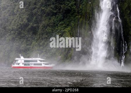 Das Kreuzschiff Pride of Milford of Red Ferries liegt näher an den 155 m hohen Stirling Falls, zum Wohle der Touristen am Milford Sound in Fiordland Stockfoto