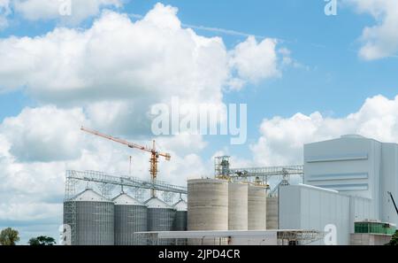 Baustelle der Futtermittelfabrik. Landwirtschaftliche Silo in der Futtermittelfabrik. Tank für Lagergetreide in der Futtermittelherstellung. Saatgutturm für Pendler Stockfoto