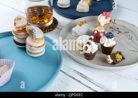 Gestapelte Macarons, umgeben von einem Glas Whiskey und schickem Blick auf die Hochzeitsbonbons. Stockfoto