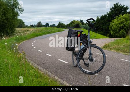 Ochten, Gelderland, Niederlande - 07 12 2022 Trekkingrad steht auf einem Radweg am Deich des Flusses Waal Stockfoto