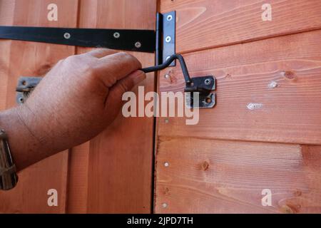 POV Hand öffnen oder schließen eine neue Holzschuppen Tür Stockfoto