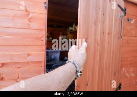 POV Hand öffnen oder schließen eine neue Holzschuppen Tür Stockfoto