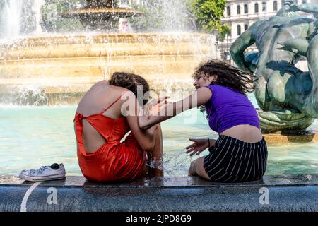 Junge Menschen kühlen sich während des heißesten Tages ab, der je in der Hauptstadt London aufgezeichnet wurde, in den Fountains am Trafalgar Square. Stockfoto