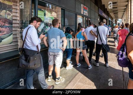 Menschen stehen vor dem Tesco Express Supermarkt in Westminster an dem heißesten Tag, der je in London, London, Großbritannien, aufgezeichnet wurde. Stockfoto