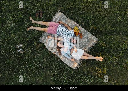 Luftaufnahme von oben nach unten, mit einem Paar mittleren Alters, das auf dem Feld ein Picknick genießt, kaukasischen Mann und Frau, die auf einer Decke liegen Stockfoto