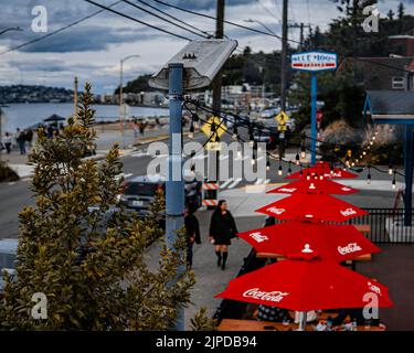 Ein hoher Winkel von Menschen, die auf einer Straße neben einem Café im Freien mit roten Coca-Cola-Schirmen spazieren Stockfoto