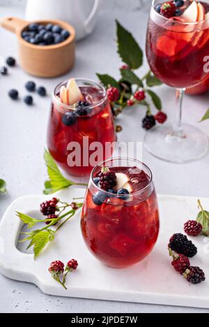 Fallen Sie Beeren und ApfelSangria in ein Glas mit Eis Stockfoto