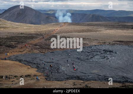 Wanderer passieren das alte Lavafeld auf dem Weg zum Ausbruch des Meradalir Vulkans, Reykjanes Peninsula, Island, August 2022. Stockfoto