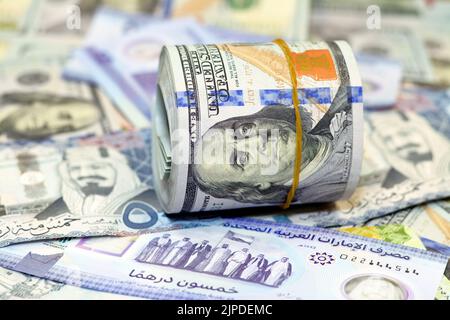 American Money roll with a Band on a pile of American Dollar Geldscheine American Cash Money Banknoten mit Saudi-Arabien riyals Geldscheine und New Emir Stockfoto