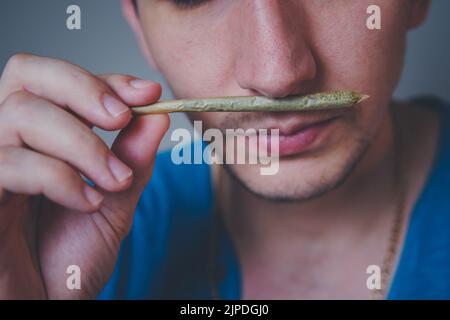 Nahaufnahme eines erwachsenen Mannes leuchtet mit Streichhölzern und rauchenden medizinischen Marihuana-Gelenken auf. Konzept der pflanzlichen und alternativen Medizin Stockfoto