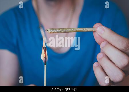 Nahaufnahme eines erwachsenen Mannes leuchtet mit Streichhölzern und rauchenden medizinischen Marihuana-Gelenken auf. Konzept der pflanzlichen und alternativen Medizin Stockfoto