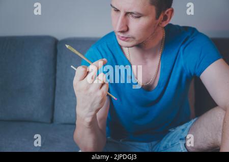 Nahaufnahme eines erwachsenen Mannes leuchtet mit Streichhölzern und rauchenden medizinischen Marihuana-Gelenken auf. Konzept der pflanzlichen und alternativen Medizin Stockfoto