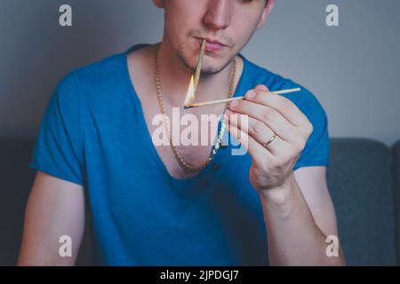 Nahaufnahme eines erwachsenen Mannes leuchtet mit Streichhölzern und rauchenden medizinischen Marihuana-Gelenken auf. Konzept der pflanzlichen und alternativen Medizin Stockfoto