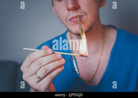 Nahaufnahme eines erwachsenen Mannes leuchtet mit Streichhölzern und rauchenden medizinischen Marihuana-Gelenken auf. Konzept der pflanzlichen und alternativen Medizin Stockfoto