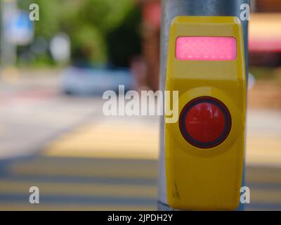 Nahaufnahme einer Signaltaste für den Fußgängerüberweg, die an einer Fußgängerüberfahrt aufgenommen wurde. Eine Ruftaste, die das Licht durchlässt. Stockfoto