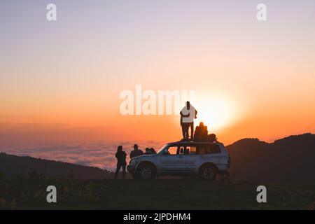 Akhmaro, Georgia - 14. august, 2022: Statische Ansicht Freunde Tour Gruppe Stand auf 4WD Dach beobachten Sonnenuntergang gemeinsam im Freien viel Spaß über Wolken in Famo Stockfoto