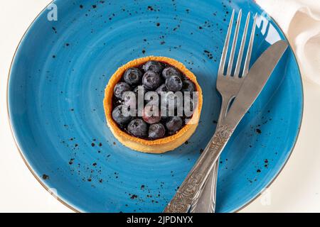 Frisch gebackene Heidelbeertarte auf einem blauen Porzellanteller Stockfoto