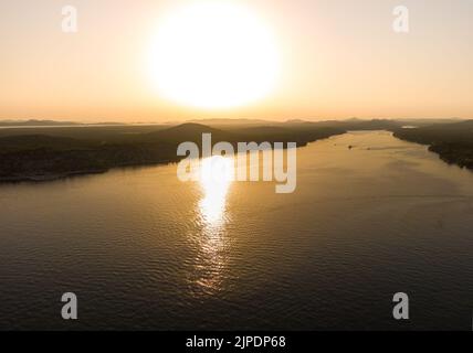 Luftdrohnenaufnahme des Sonnenuntergangs über den Kornati Inseln in der Nähe der Stadt Sibenik, Kroatien. Wasserbucht mit Booten und sanftem Sonnenlicht. Stockfoto