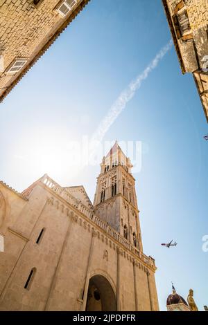 Blick auf die Kathedrale von St. Lawrence, Trogir - Kroatien. Von unten nach oben Blick auf den schönen alten Kirchturm. Das Flugzeug landet auf dem Flughafen Split. Aircr Stockfoto