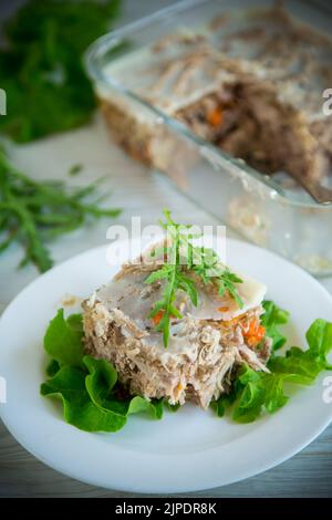 Gelees Fleisch mit Gemüse und Gemüse auf einem Teller auf einem Holztisch Stockfoto