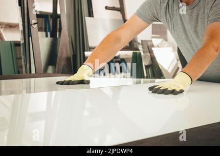 Ein Glasierer bricht eine große weiße Scheibe auf einem speziellen Tisch, Glass Factory Stockfoto