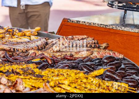 Abwechslungsreicher Fleischgrill mit Schweinefleisch, Hähnchenspießen, Würstchen und Chorizos, selektiver Fokus auf Schweinebrippen. Stockfoto