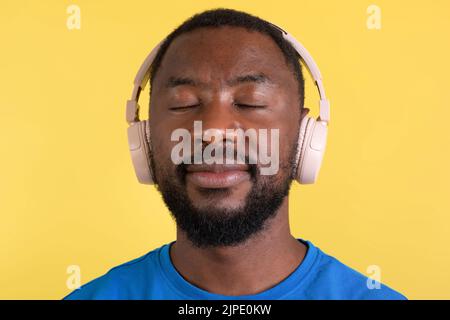 Porträt Des Afrikanischen Mannes Hörmusik Tragen Von Kopfhörern, Gelber Hintergrund Stockfoto