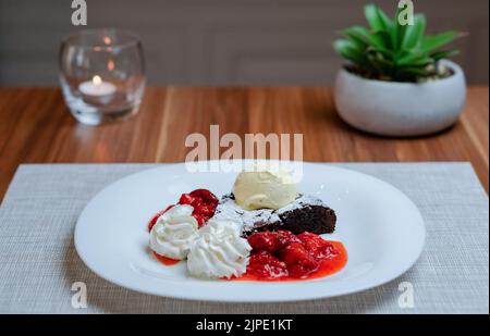 Brownie mit dunkler Schokolade, Schlagsahne, Eiscreme und Erdbeerpüree Stockfoto