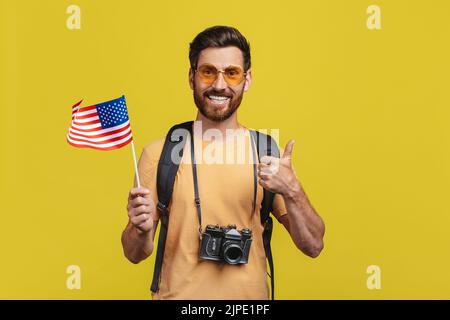 Auslandsreisen. Männlicher Tourist mit USA-Flagge und Daumen hoch, Mann mittleren Alters bereit für den Urlaub Stockfoto