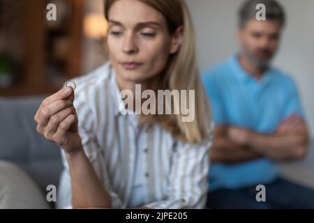 Unglückliche traurige Erwachsene kaukasische Frau, die Ring hielt und enttäuschten Mann im Wohnzimmer ignorierte, aus nächster Nähe Stockfoto