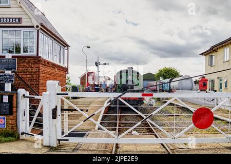 Dampfzug am Bahnsteig über das Bahnübergang im Bahnhof bei Lincolnshire Wolds Railway, Ludborough, England, Großbritannien Stockfoto