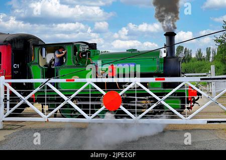 Dampfzug überquert Straße über Bahnübergang bei Lincolnshire Wolds Railway, Ludborough, England, Großbritannien Stockfoto