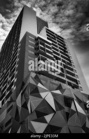 Eine vertikale Aufnahme eines Gebäudes mit Architekturglas unter den Wolken Stockfoto