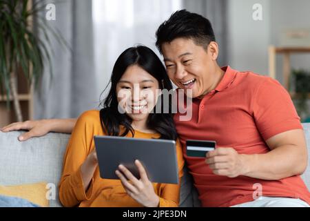 Aufgeregt asiatische Mann und Frau mit Tablet und Kreditkarte Stockfoto