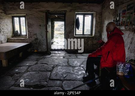 Genießen Sie an einem regnerischen Tag in den Lakeland Fells in Warnscale Head Bothy auf Fleetwith Pike im Lake District, Großbritannien, Speisen und ein heißes Getränk Stockfoto