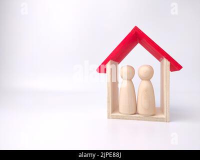 Die hölzernen Puppenfiguren von Paar und Spielzeughaus auf weißem Hintergrund Stockfoto