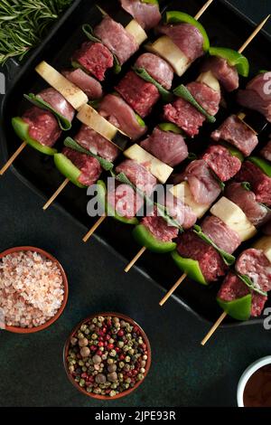 Rohe Fleischspieße vor dem Kochen auf dunklem Hintergrund. Stockfoto