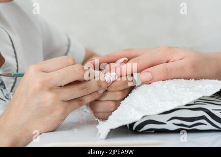 Detail der Hände eines Manikuristen, der eine ordnungsgemäße Reinigung der Nägel durchführt, um mit dem Malen und Dekorieren zu beginnen. Körperpflege und Handpflege. Konzept o Stockfoto