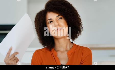 Porträt afroamerikanische nachdenkliche Frau mit lockigem Haar fühlt sich im Sommer hohe Hitze stickig winkende Papiere Dokumente machen Wind denkt Planung Stockfoto