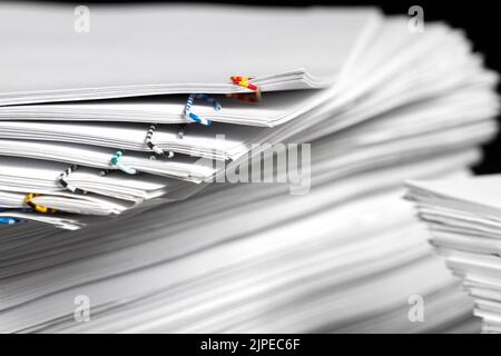 Stapel von Papieren mit bunten Büroklammern auf dunklem Hintergrund Stockfoto