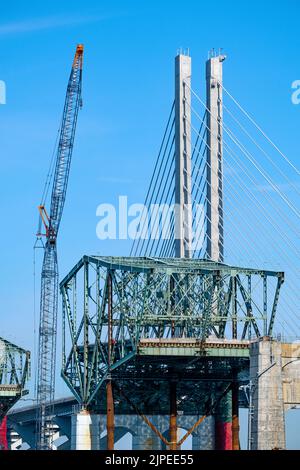 Eine alte Brücke wird gerade abgerissen, neben einer neuen Brücke mit Kabelgestasten. Stockfoto