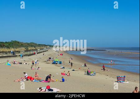 Leute, die sich an einem heißen, sonnigen Tag am Strand in Skegness entspannen Stockfoto