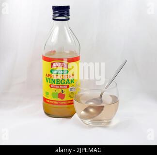 Bio Apfelessig mit Mutter - klare Flasche mit kleinem Glas und Teelöffel. Stockfoto