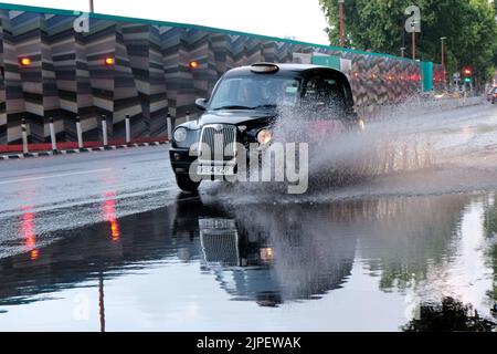 London, Großbritannien. 17.. August 2022. Ein schwarzes Taxi fährt durch Regenwasser entlang des Victoria Embankment, als schwere Regenschauer die Hauptstadt treffen, was zu lokalen Überschwemmungen in Teilen der Stadt führt, da die Abflüsse schwer zu bewältigen waren. Kredit: Elfte Stunde Fotografie/Alamy Live Nachrichten Stockfoto