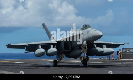 220816-N-YQ181-1221 PHILIPPINISCHES MEER (AUG 16, 2022) ein F/A-18E Super Hornet, das an das Royal Maces of Strike Fighter Squadron (VFA) 27 angeschlossen ist, landet auf dem Flugdeck des einzigen vorwärts eingesetzten Flugzeugträgers der US Navy USS Ronald Reagan (CVN 76) in der philippinischen See, 16. August. Die Royal Maces führen Luftangriff- und Streikkräfte-Escort-Missionen sowie Schiffe, Kampfgruppen- und Geheimdiensteintreibemissionen durch. Ronald Reagan, das Flaggschiff der Carrier Strike Group 5, stellt eine kampfbereite Truppe zur Verfügung, die die Vereinigten Staaten schützt und verteidigt, und unterstützt Allianzen, partnersch Stockfoto