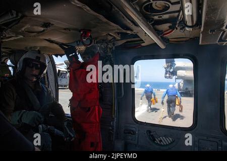220809-N-IV962-3019 Seeleute beenden das Abheben von Niederzurrketten von einem MH-60s Seahawk, der dem Hubschrauber-Seekampfschwadron (HSC) 21 zugewiesen wurde und derzeit mit dem amphibischen Angriffsschiff USS Makin Island (LHD 8) am 9. August an Bord ging. Makin Island hat die Fähigkeit, alle Marine-Luftfahrtanlagen einschließlich der MV-22 Osprey und der F-35B Lightning II zu bestieden und zu unterstützen Makin Island, das Flaggschiff der Amphibiengeschwader (CPR) SEVEN, und die 13. Marine Expeditionary Unit (MEU) führen derzeit integrierte Schulungen in der US-3.-Flotte durch, um sich auf einen bevorstehenden Einsatz vorzubereiten. (USA Navy Foto von M Stockfoto
