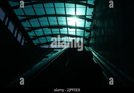 Bukarest, Rumänien - 22. Juni 2021: Die Reflexion des Lichts, das durch die verglaste Decke geht, leuchtet in starkem Kontrast auf der Rolltreppe am e Stockfoto