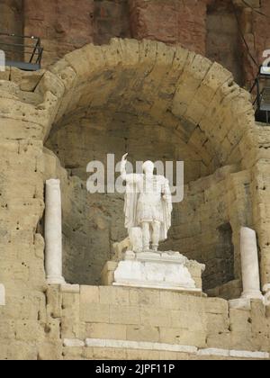 Die Rückwand des Antiken Theaters von Orange mit einer Nische, in der sich eine Statue des Apollo befindet, bildet den Hintergrund für das römische Amphitheater. Stockfoto