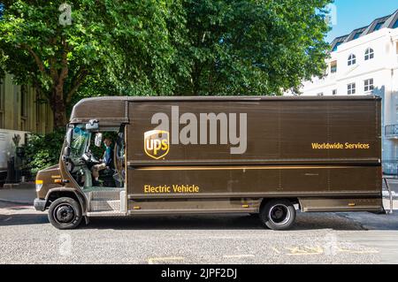 London, Großbritannien - 5. Juli 2022: Nahaufnahme, UPS Brown Delivery Electric Van in Albany Street, Fahrer auf dem Sitz, unterstützt von grünem Laub. Stockfoto