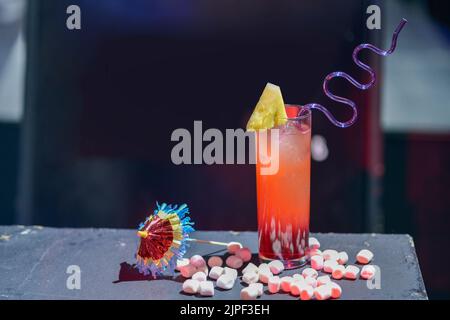 Trinken Sie mit viel erfrischendem rosafarbenem Eis, einem Stück Ananas und Gelee-Bohnen oder kleinen süßen Süssmarmelibs Stockfoto